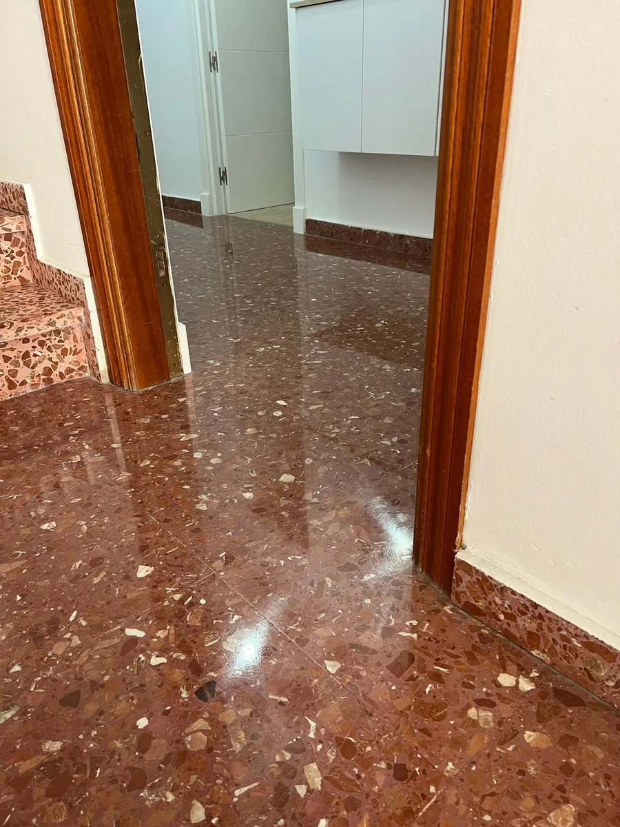 Entrada con suelo de terrazo rojo recién abrillantado